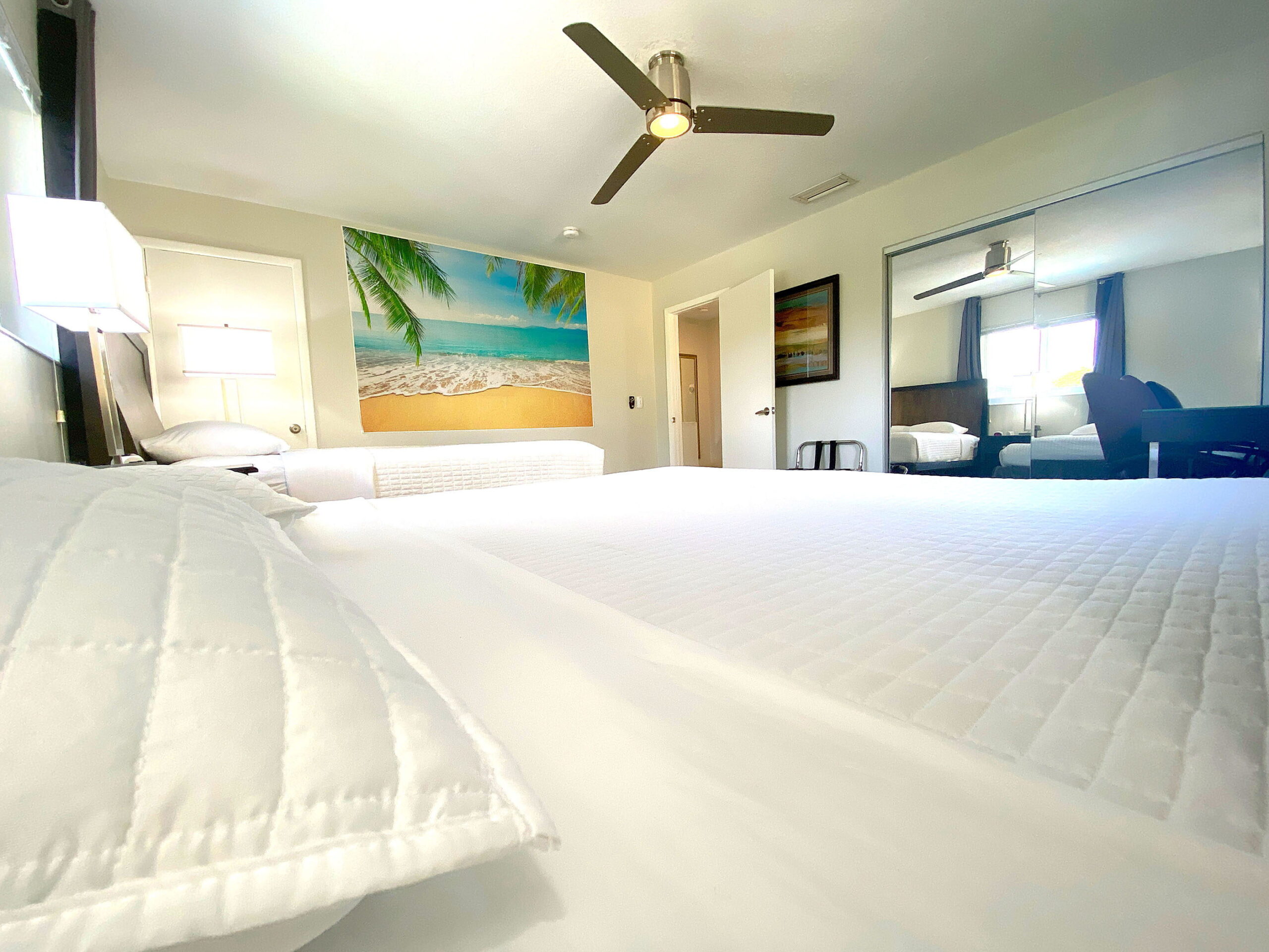 Master bedroom with two beds and tropical wall art at Tarpon Harbor 1
