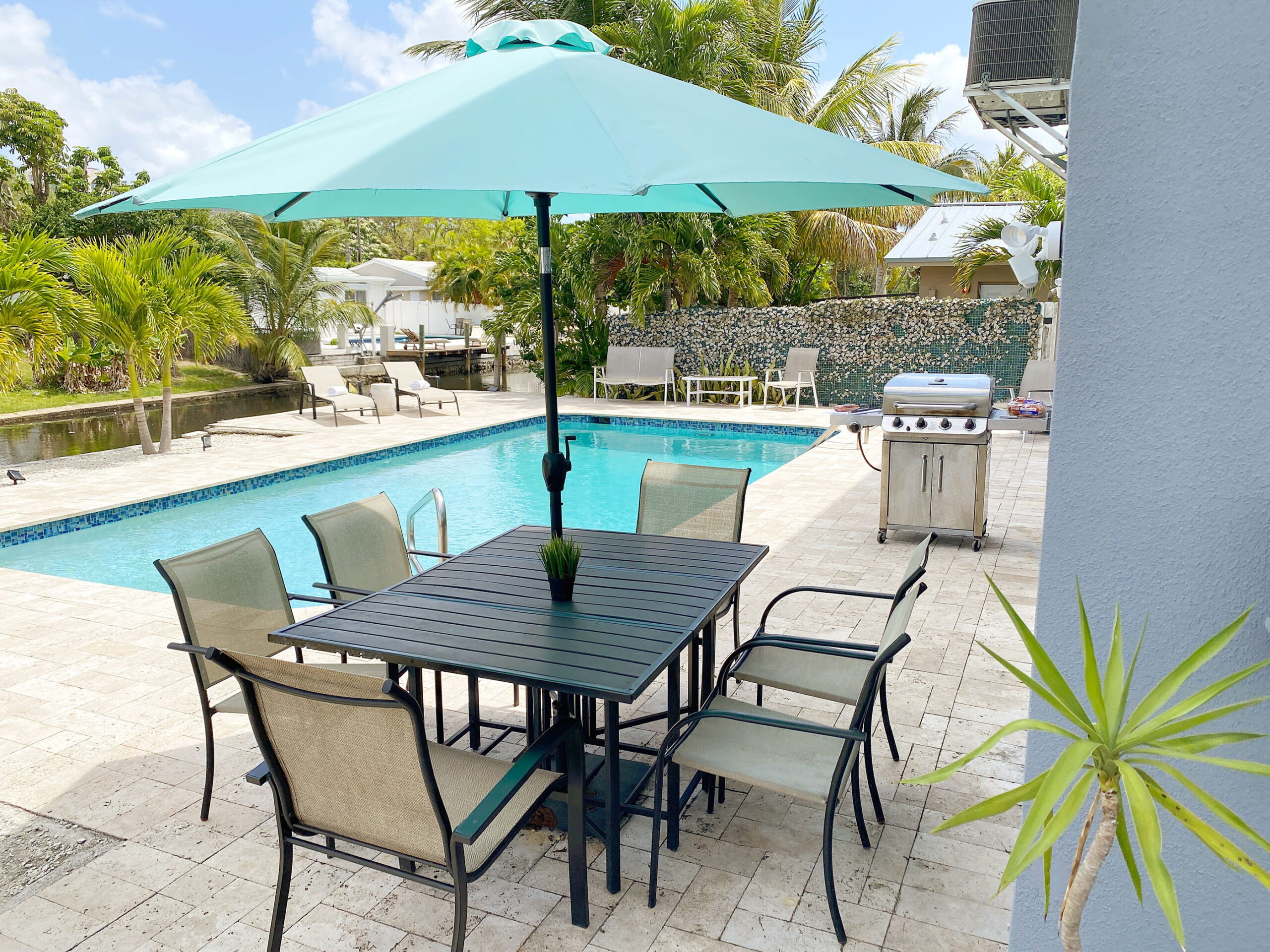 Poolside dining area with umbrella, outdoor table and grill at Tarpon Harbor 1